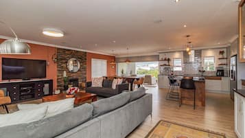 Een moderne woonkamer met een grote grijze bank, een flatscreen televisie en een stenen muur.