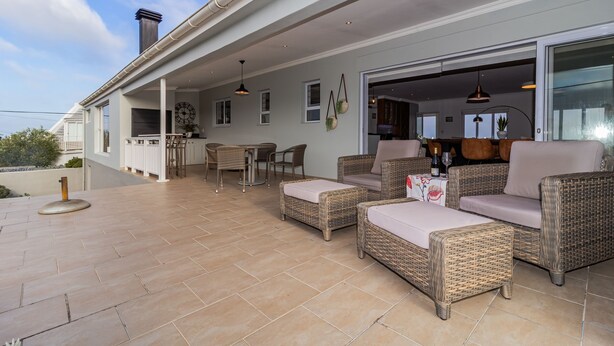 Un espace extérieur aménagé en terrasse, avec des meubles en osier, une table à manger et des chaises.