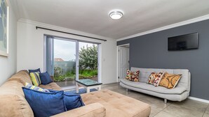Un salon avec un canapé beige, un canapé gris et une table basse en verre.