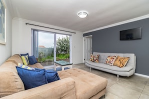 Ein Wohnzimmer mit einem beigefarbenen Sofa, einem grauen Sofa und einem Glastisch.