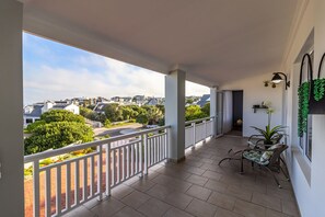 A balcony with a view of a residential area, a potted plant, and a seating area. - Villa Azure, Vermont Home with Studio, Mountain & Sea Views (Vermont)