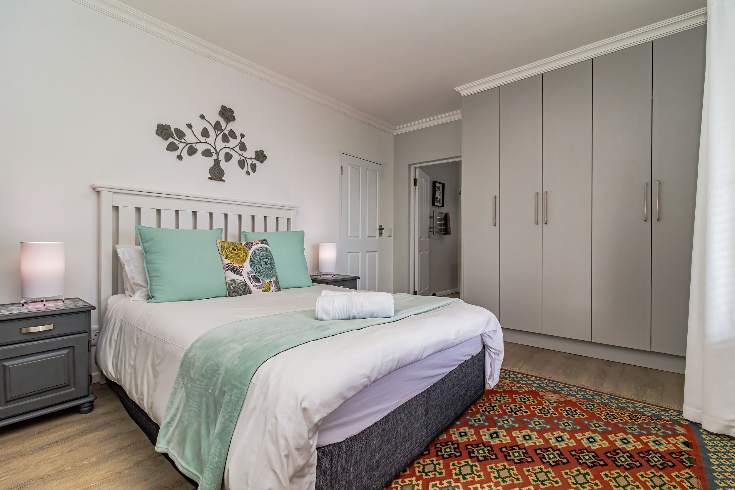 A bedroom with a bed, nightstands, a wardrobe, and a decorative wall piece.