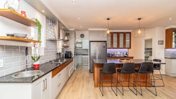 Een moderne keuken met een centraal eiland, barkrukken en een ingebouwde oven.