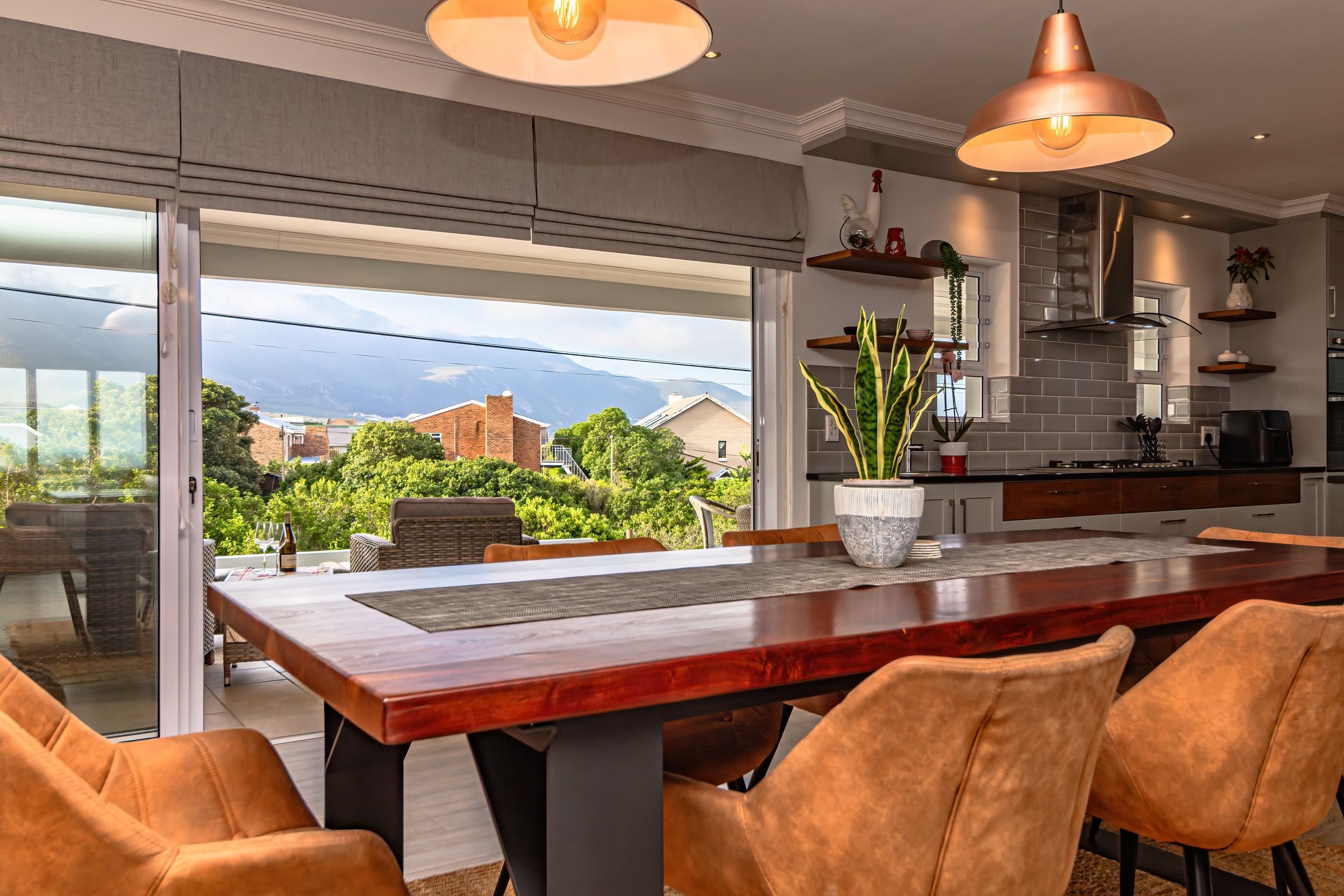 A modern kitchen with a large island, pendant lighting, and a view of a mountainous landscape.