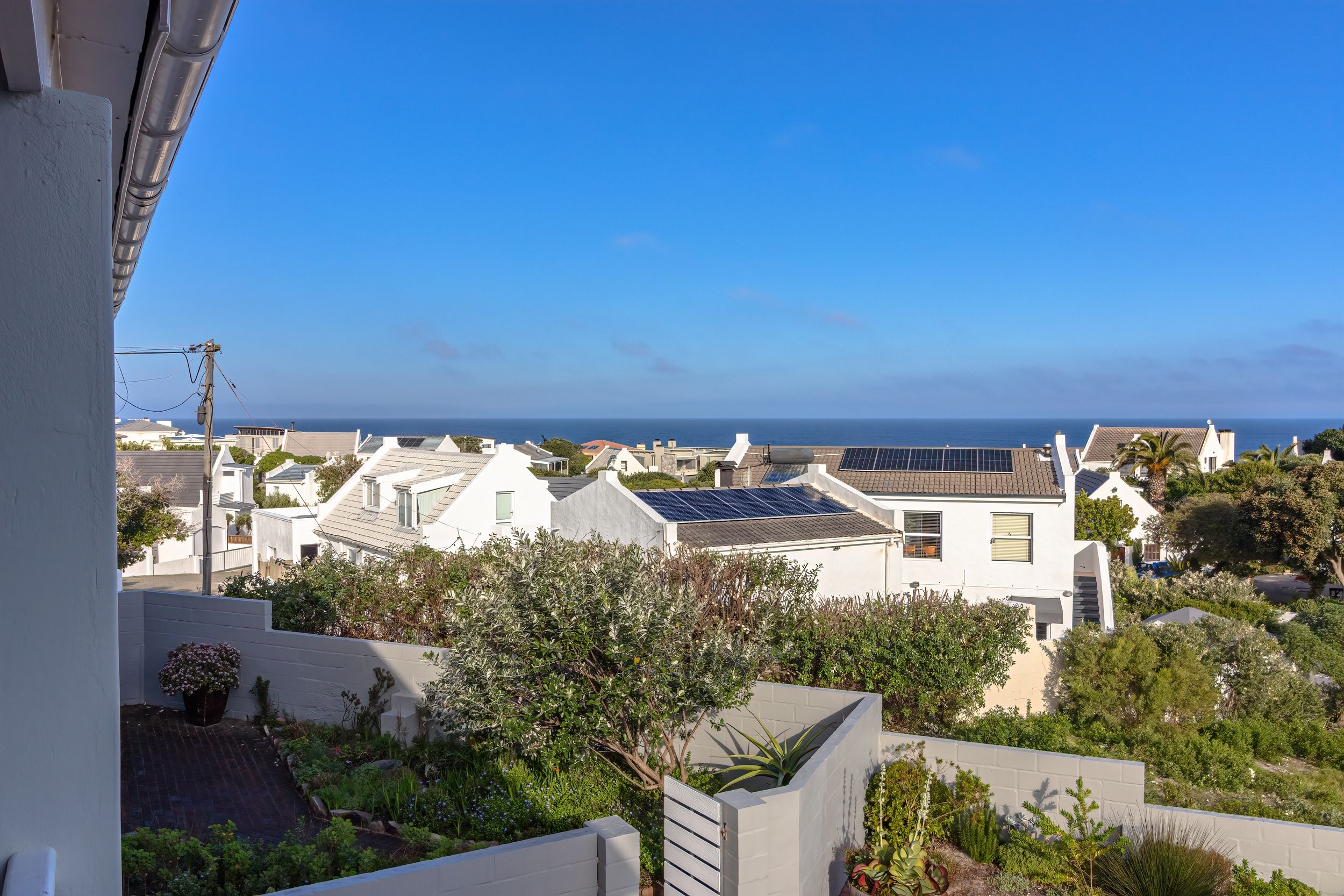 Ein Wohngebiet mit Häusern, einige davon mit Solaranlagen, und Blick auf das Meer.