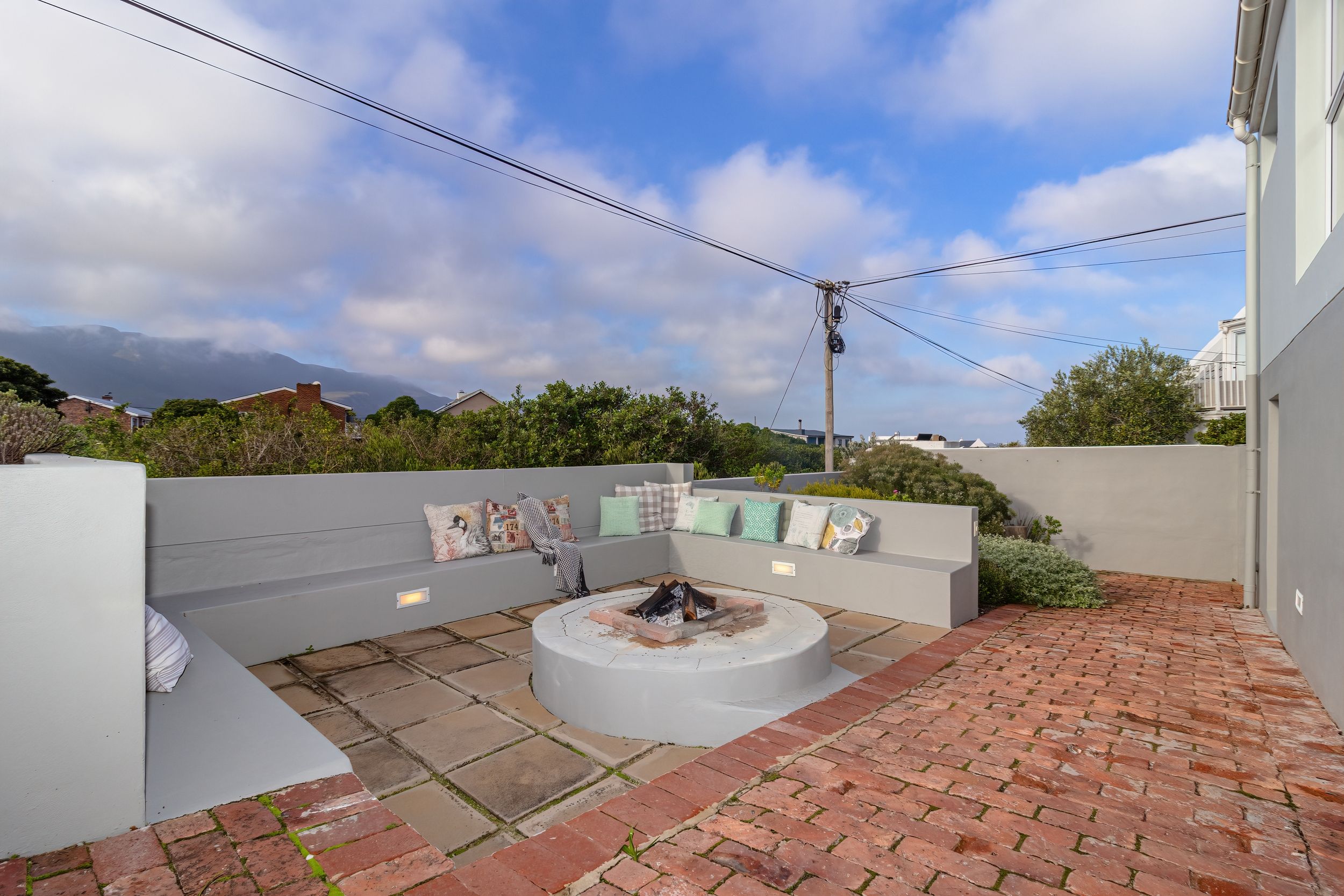 A rooftop patio with a fire pit, seating area, and a view of the sky and distant mountains.