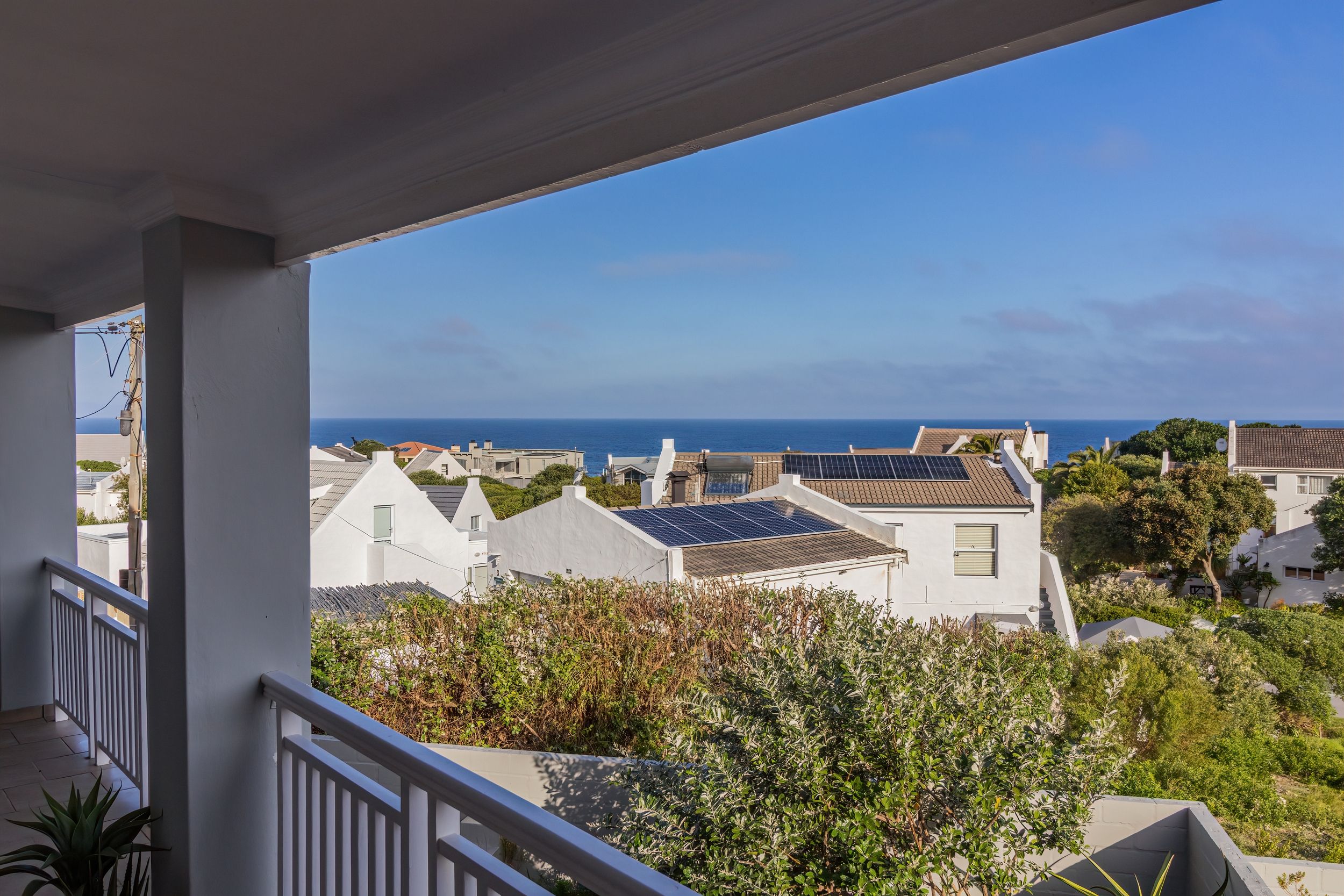 A residential area with houses, a balcony, and a view of the sea.