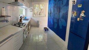 A kitchen with white cabinets, a stove, a sink, and a blue refrigerator. - "Pinetina" Beach Villa (Palermo)