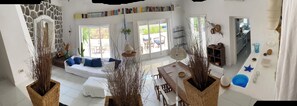 A spacious living area with a white sofa, a dining table, and a kitchen visible through an open door. - "Pinetina" Beach Villa (Palermo)