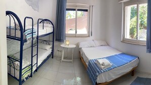 A bedroom with bunk beds, a single bed, a small table with a lamp, and windows with curtains. - "Pinetina" Beach Villa (Palermo)
