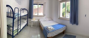 A bedroom with bunk beds, a single bed, a small table with a lamp, and windows with curtains. - "Pinetina" Beach Villa (Palermo)
