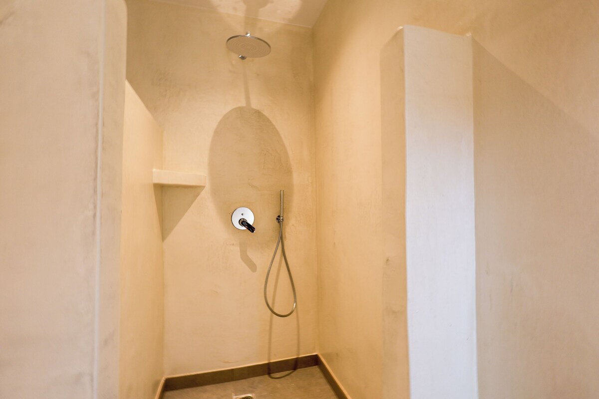 Ein kleiner, abgeschlossener Duschbereich mit Handbrause und am Wand montierter Armatur.
