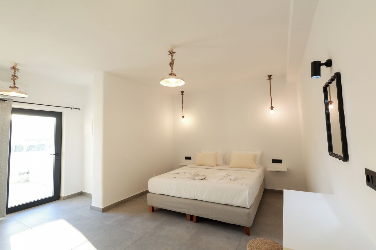 A bedroom with a bed, bedside tables, a ceiling light fixture, and a wall-mounted mirror.