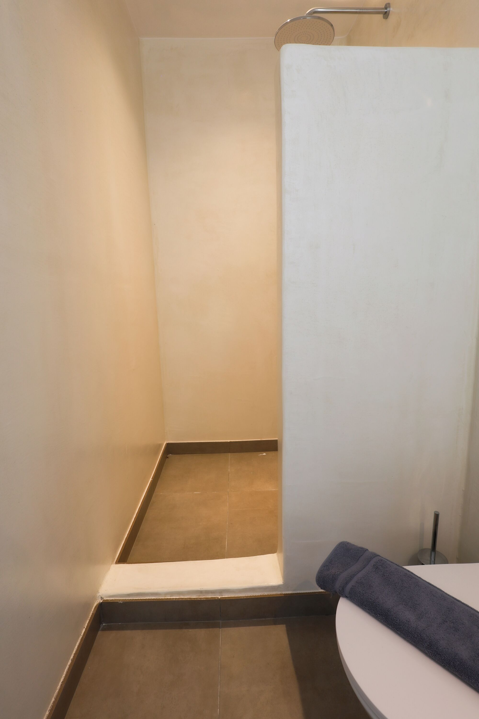 A bathroom with a shower, a towel, and a toilet.