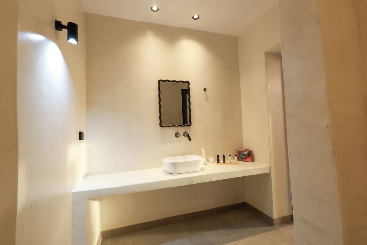 A modern bathroom with a white sink, a mirror, and a towel rack.