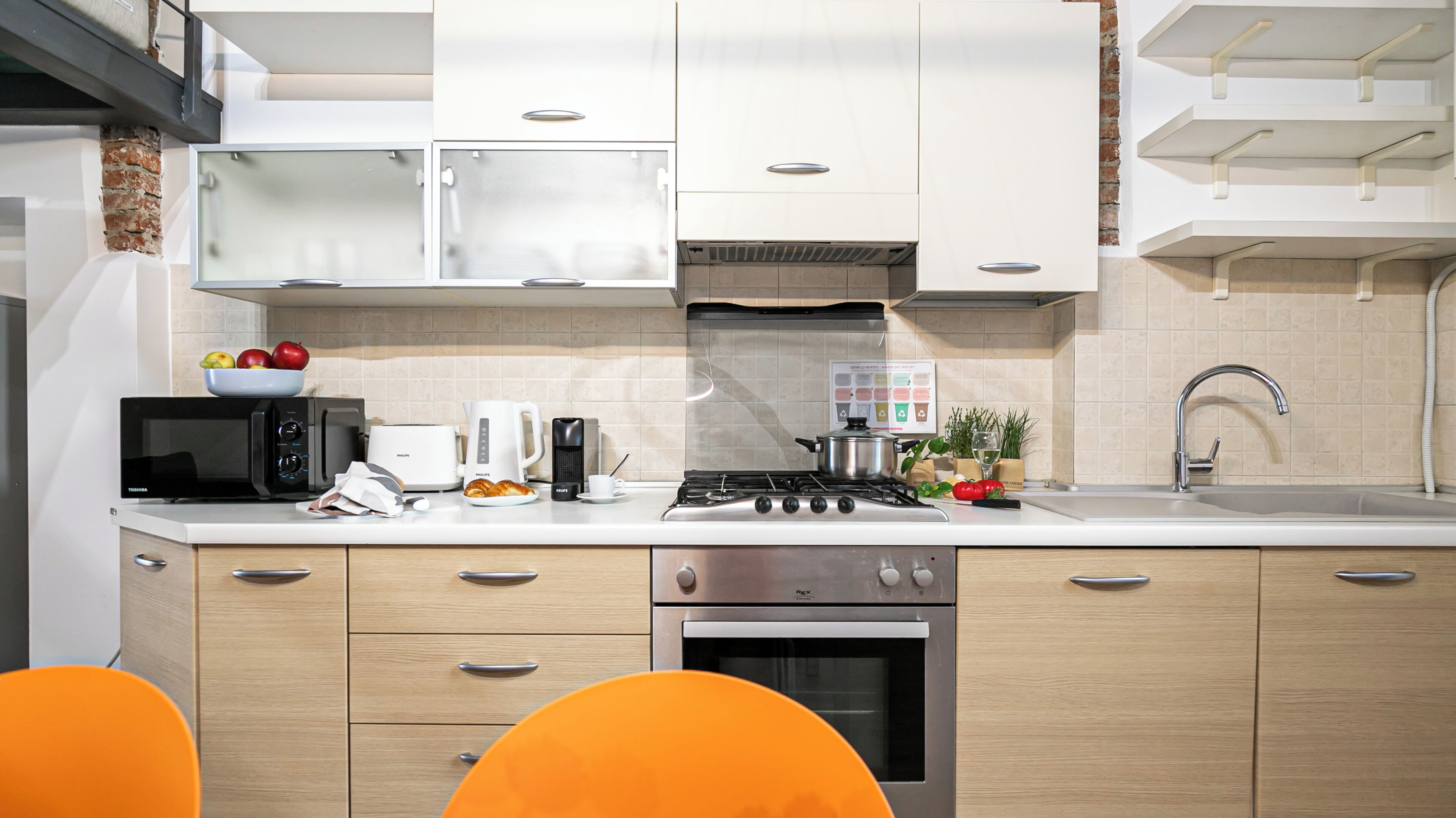 A modern kitchen with white cabinets, a stove, a microwave, and a sink.