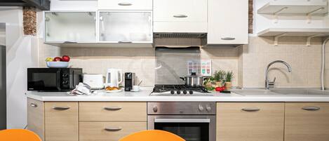 A modern kitchen with white cabinets, a stove, a microwave, and a sink.