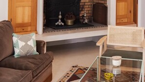 A living room with a fireplace, a sofa, a glass coffee table, and a chair. - Villa Between the Pines and the Beach – Sleeps 8 – Pereire (Audenge)