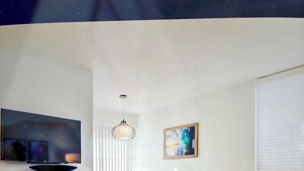 Ein modernes Wohnzimmer mit einer Couch, einem kleinen runden Tisch, einem Fernseher und einem Essbereich mit Stühlen und einem Tisch.
