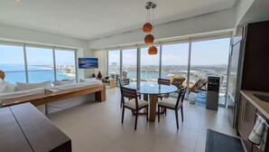 A modern hotel room with a large window, a dining area, and a kitchen. - Icon Vallarta 2-2501, 1 bedroom with ocean view (Puerto Vallarta)