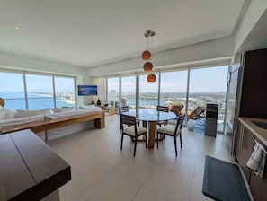 A modern hotel room with a large window, a dining area, and a kitchen. - Icon Vallarta 2-2501, 1 bedroom with ocean view (Puerto Vallarta)