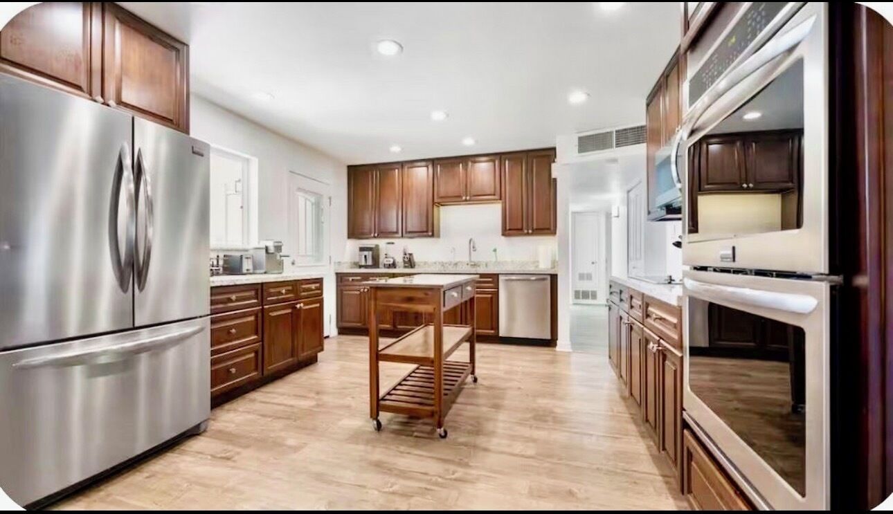 A modern kitchen with stainless steel appliances, wooden cabinets, and a central island.