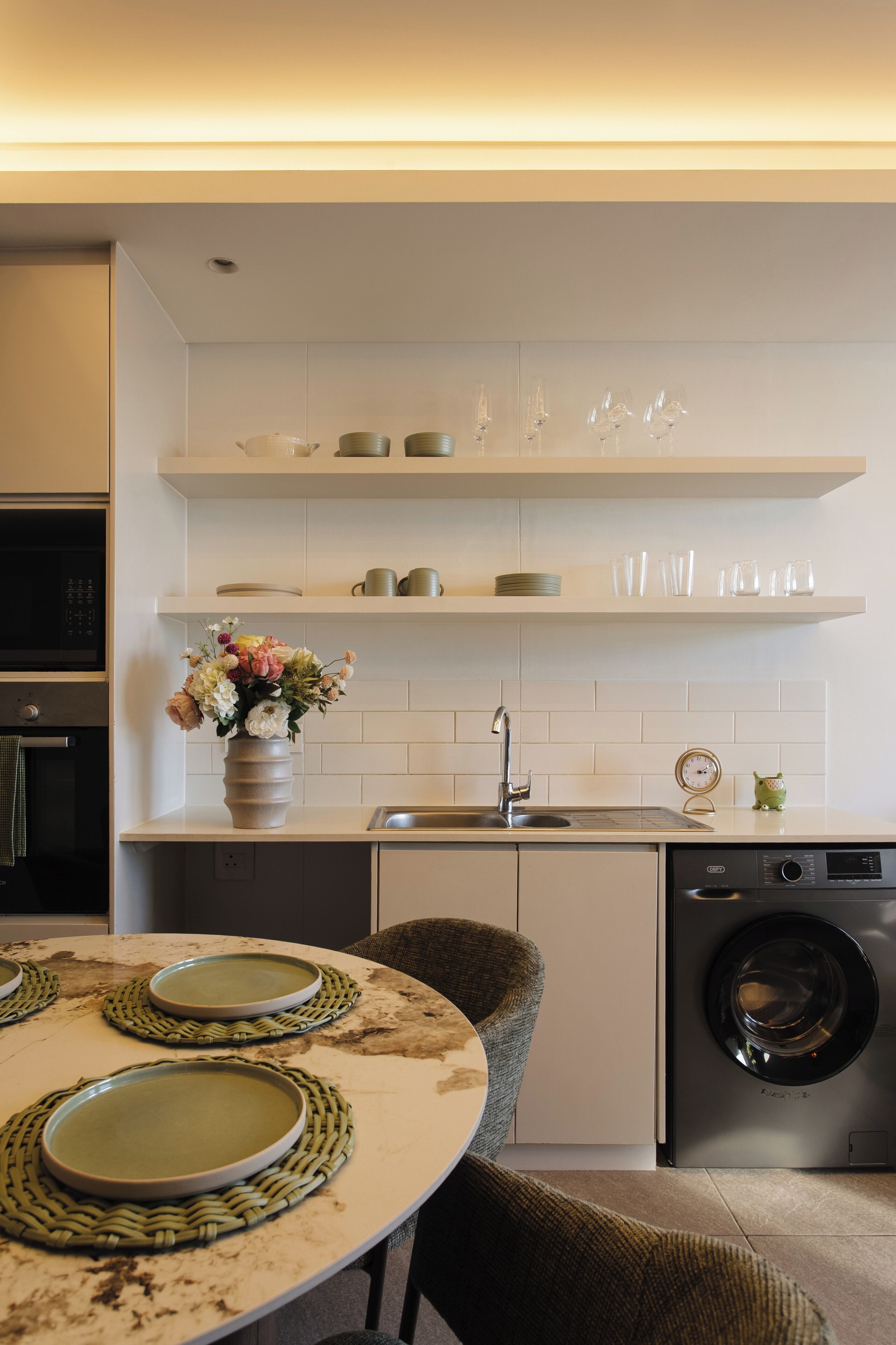 Una cocina moderna con armarios blancos, horno integrado, lavavajillas y lavadora.