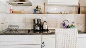 Una cocina con cafetera, hervidor y una cesta sobre la encimera.