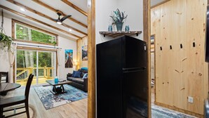 A modern kitchen with a black refrigerator, wooden ceiling beams, and a dining area with a table and chairs.
