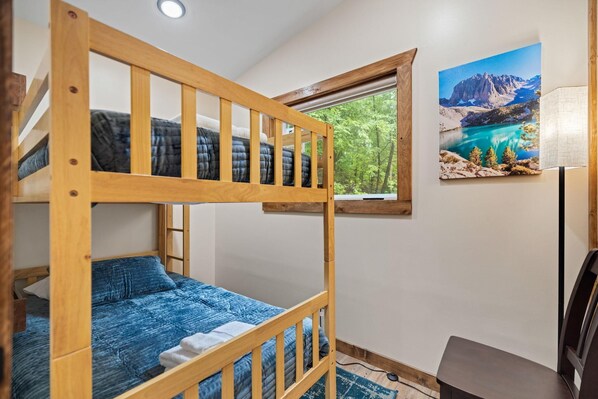 Dormitorio con literas, una ventana, un cuadro y un escritorio.