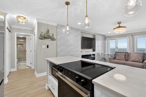 A modern kitchen with a central island, a dining area with a sofa, and a view of the sea. - Beachfront Condo dr 1402 (Virginia Beach)