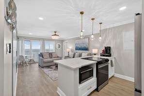 A modern kitchen with a central island, built-in ovens, and pendant lighting. - Beachfront Condo dr 1402 (Virginia Beach)