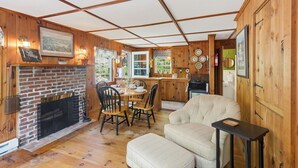 Un intérieur de chalet chaleureux avec une cheminée, un coin repas et une cuisine.