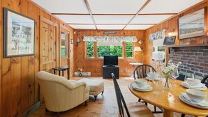 Un intérieur en bois comprenant une table à manger pour quatre personnes, un canapé et un téléviseur.