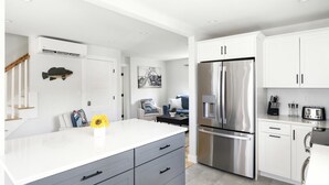 Eine moderne Küche mit weißen Schränken, einem Edelstahl-Kühlschrank und einem integrierten Wasserspender.
