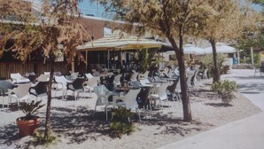 An outdoor cafe with tables and chairs, umbrellas, and potted plants. - Mare`s Home (Sibenik)