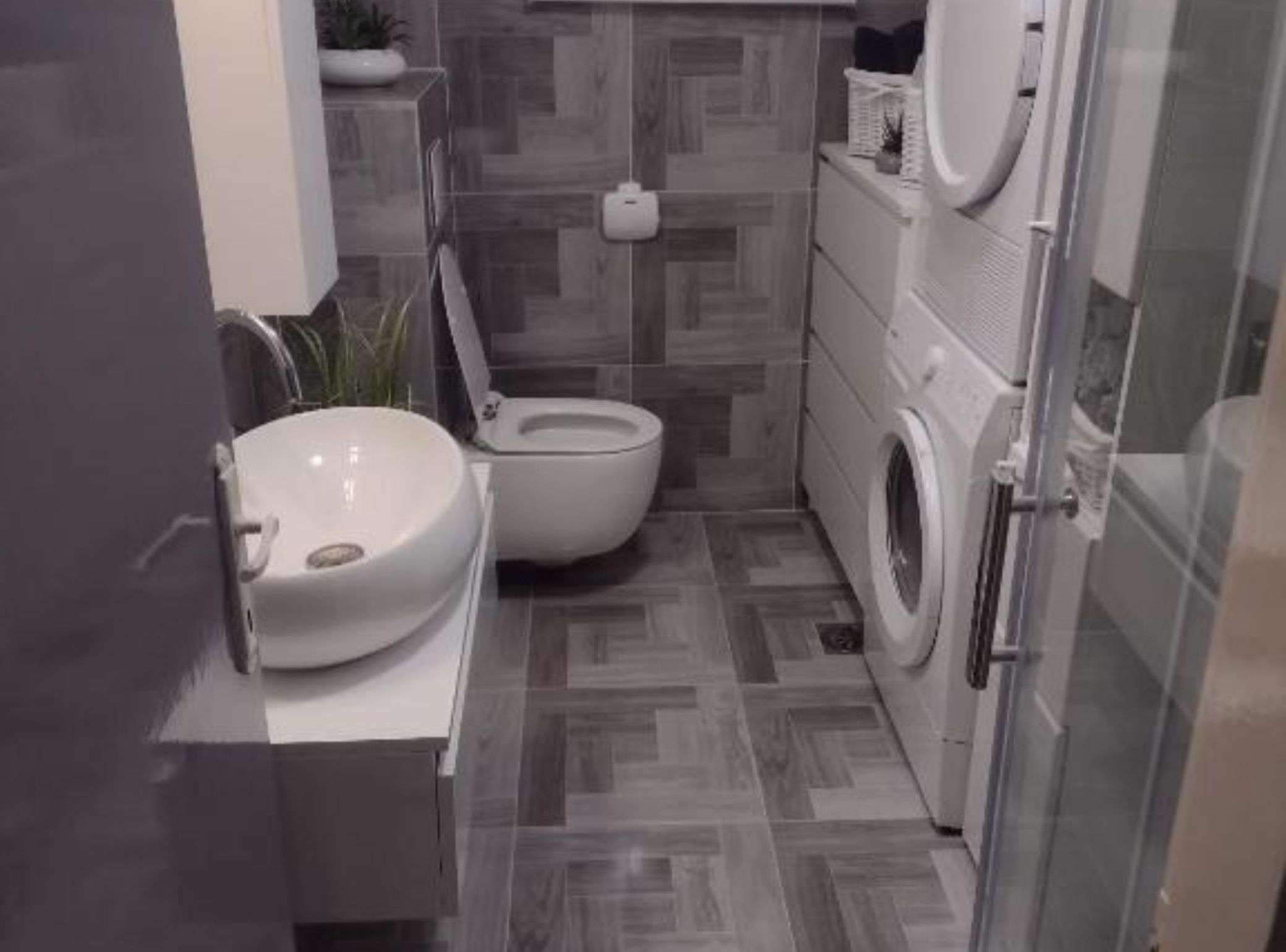 A compact bathroom with a toilet, sink, and washing machine.