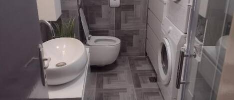 A compact bathroom with a toilet, sink, and washing machine.