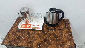 A wooden table with a tray containing a kettle, cups, and tea packets. - Embassy Gate Residency  (Chennai)
