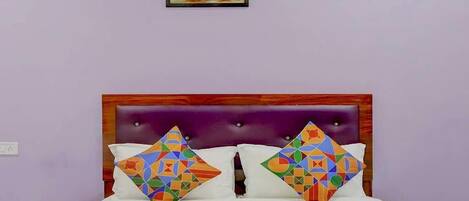 Un lit avec une couvre-lit à motifs géométriques, une tête de lit violette et deux oreillers aux motifs similaires.