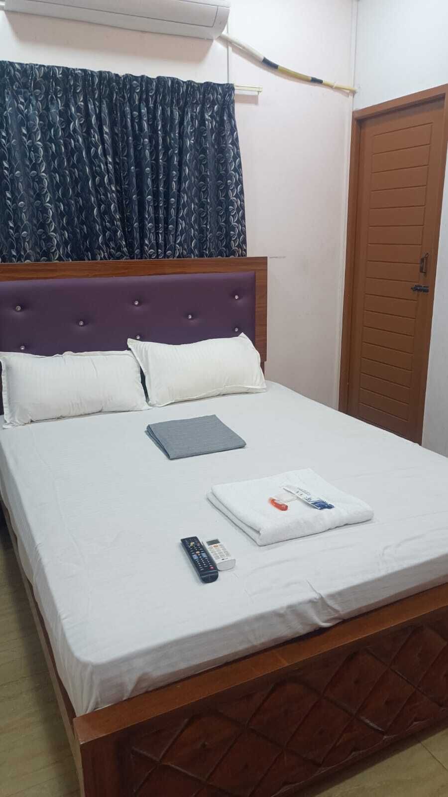 Una cama bien hecha con ropa blanca, un control remoto y una toalla doblada sobre la cama.