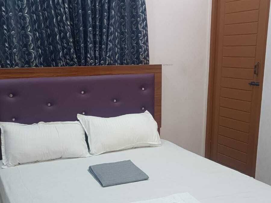 Una cama bien hecha con ropa blanca, un control remoto y una toalla doblada sobre la cama.