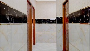 A corridor with marble flooring and walls, leading to a door with a red frame. - Embassy Gate Residency  (Chennai)