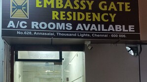 An embassy gate residency with a glass door, a fan, a chair, and a small table inside. - Embassy Gate Residency  (Chennai)