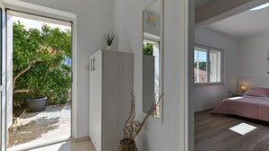 Une pièce avec un lit, une fenêtre, une porte et une plante.