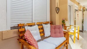 A wooden bench with white cushions and red polka dot pillows, a small table with chairs, and a heart-shaped decoration on the wall. - Apartment Sabo (Rijeka)