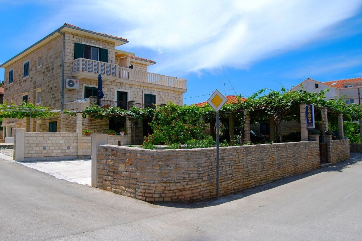 A stone building with a balcony, a clear sky, and a road in front.