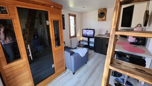 Un espacio habitable compacto con kitchenette, televisor y sofá.
