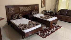 A room with two beds, a sofa, a coffee table, and a patterned rug.