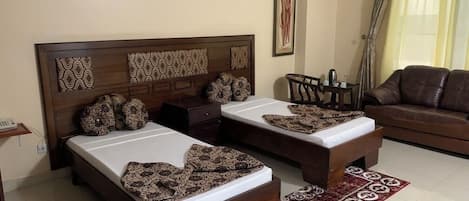 A room with two beds, a sofa, a coffee table, and a patterned rug.